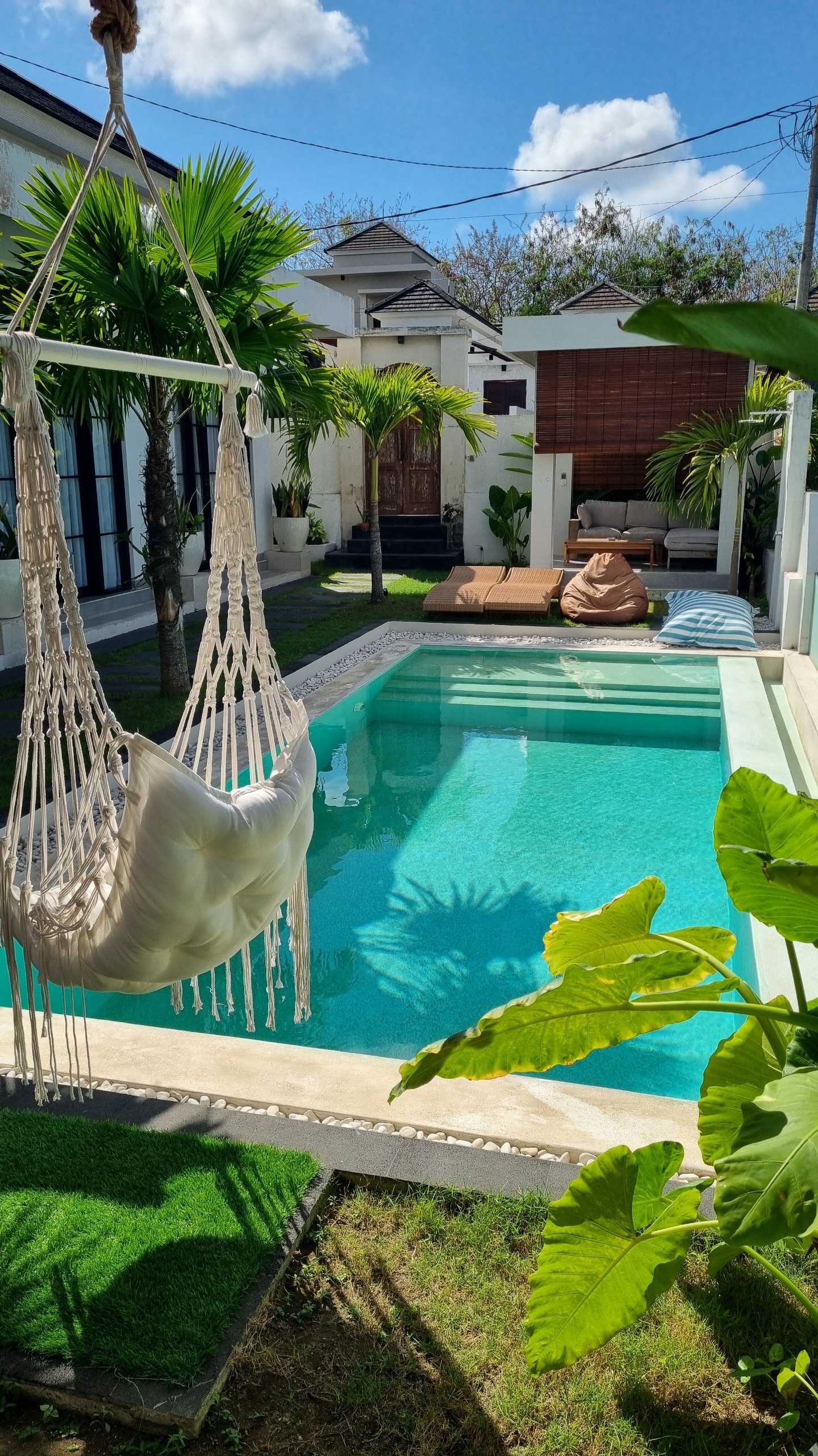 Macrame hammock chair beside the turquoise pool on a sunny day
