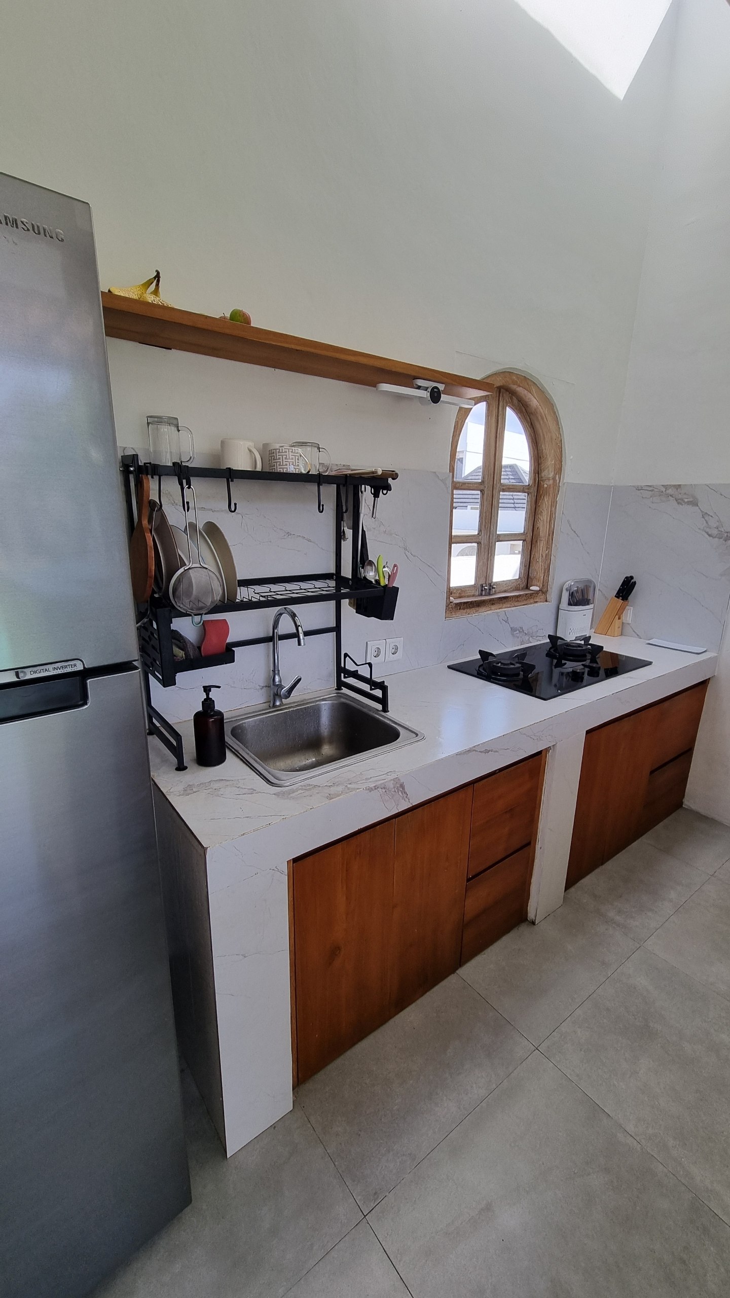 Kitchen sink and stove with a marble backsplash and arched window
