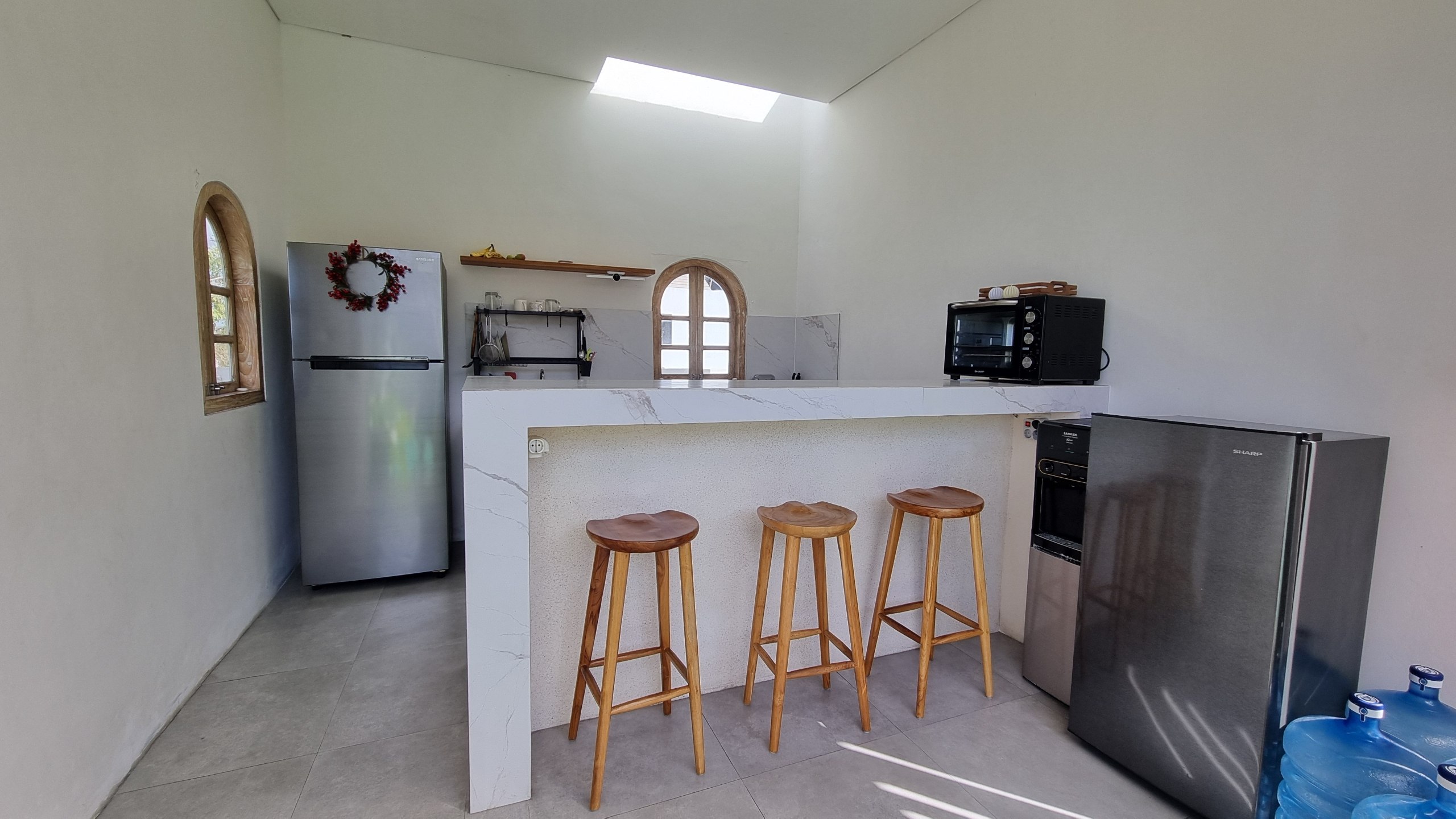 Shared kitchen with a marble bar, teak stools and arched windows