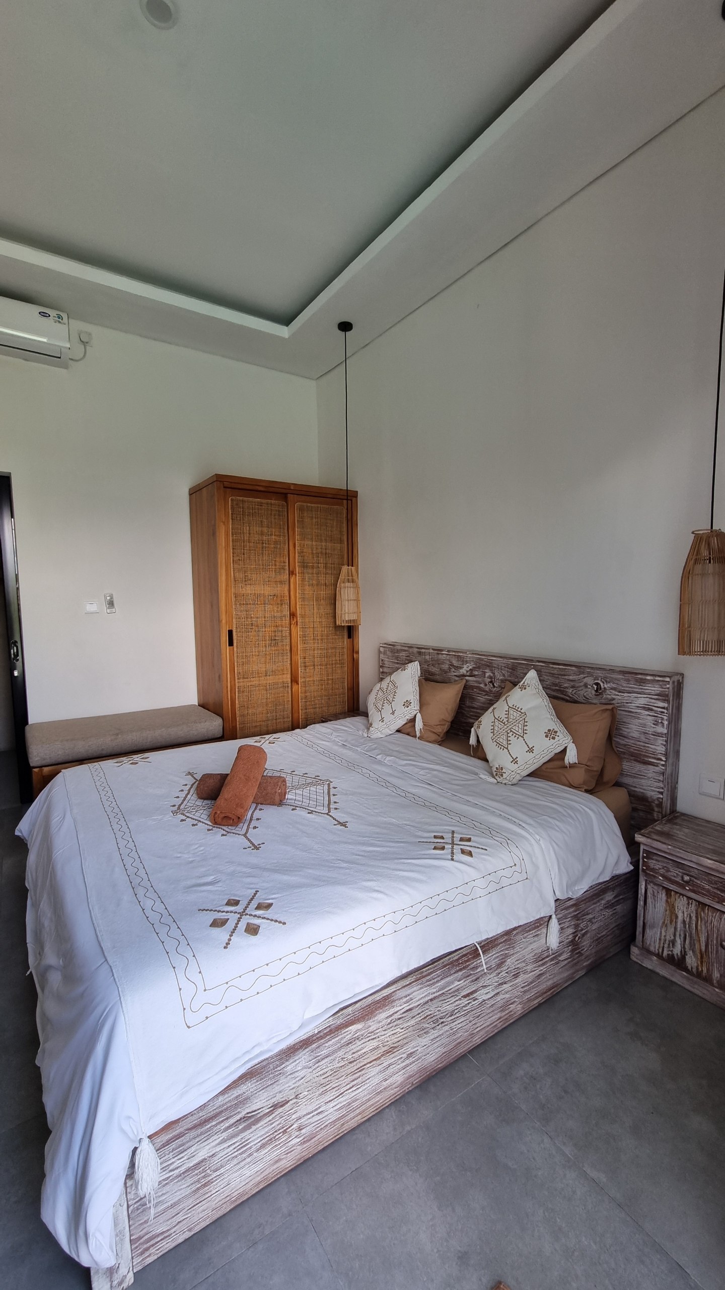 Double bed with woven pendant lights and a rattan wardrobe