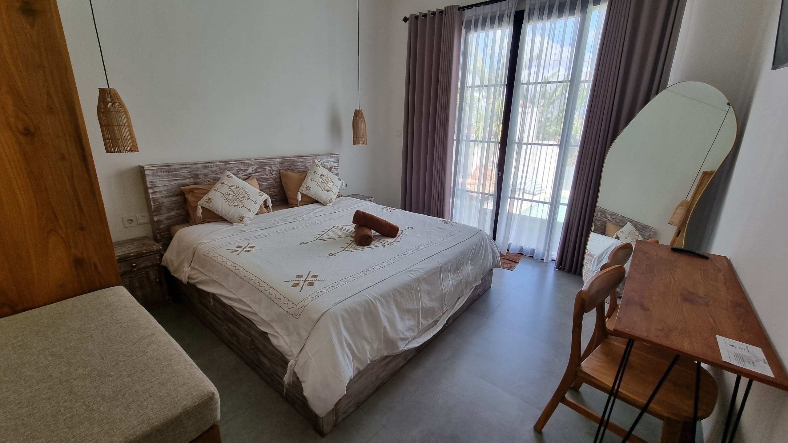 Bedroom with a whitewashed teak bed, curtains and a desk with mirror